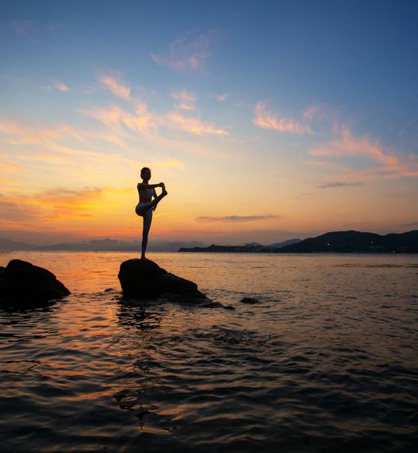 Silhouette of a person in a warrior yoga pose during sunset.